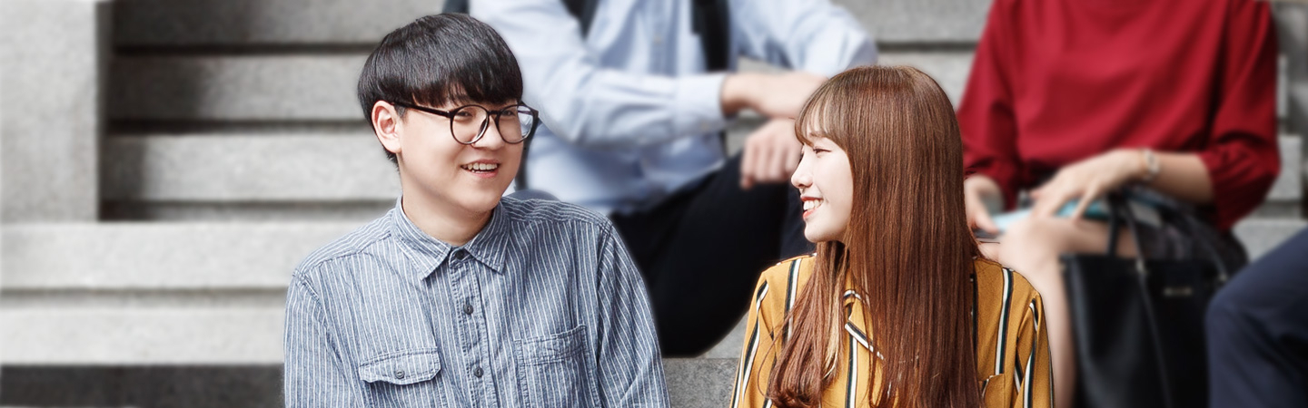 야외 계단에서 두 학생이 서로 마주 보며 이야기 나누는 모습 사진